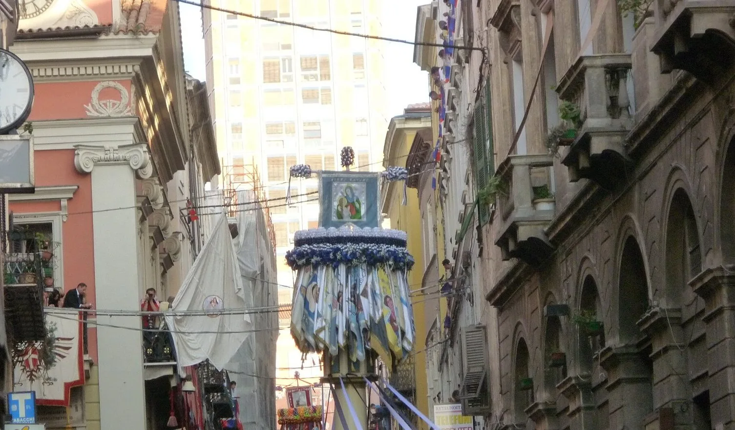 Un candeliere decorato con nastri colorati portato lungo una via del centro storico di Sassari durante la Faradda